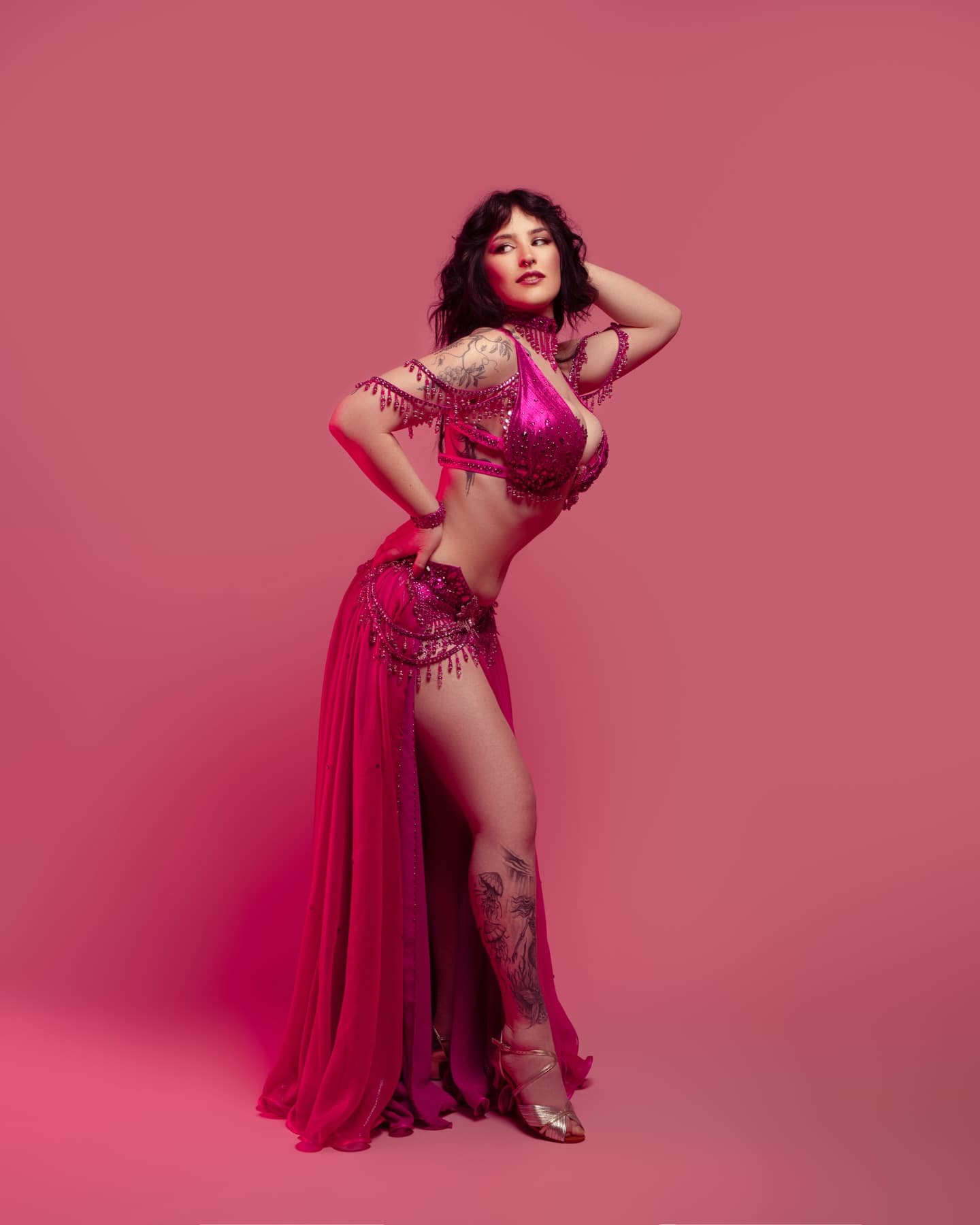 Maja Amani in a pink costume, posing against a pink backdrop